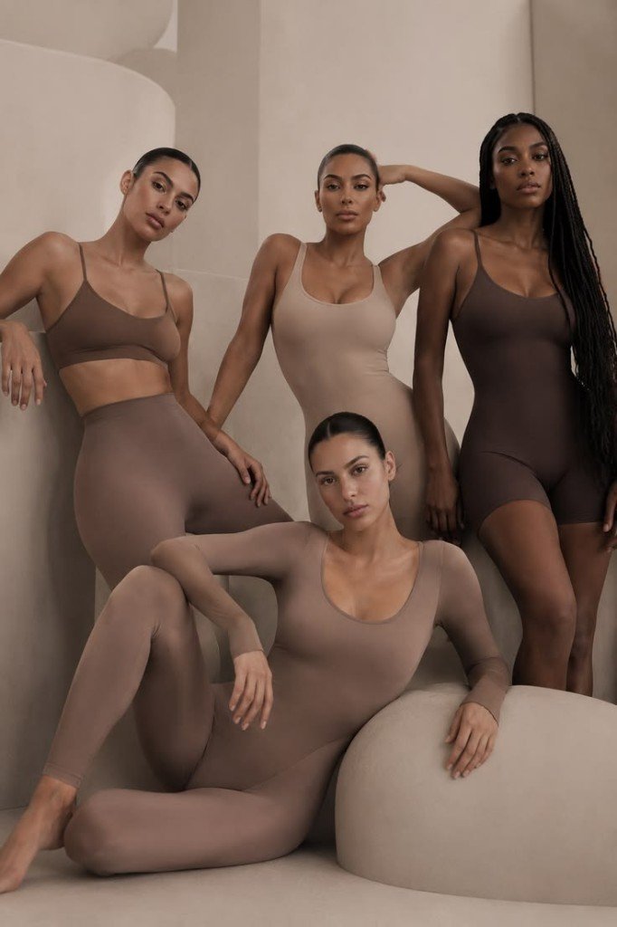 Four women modeling Jwear loungewear against curved beige architecture